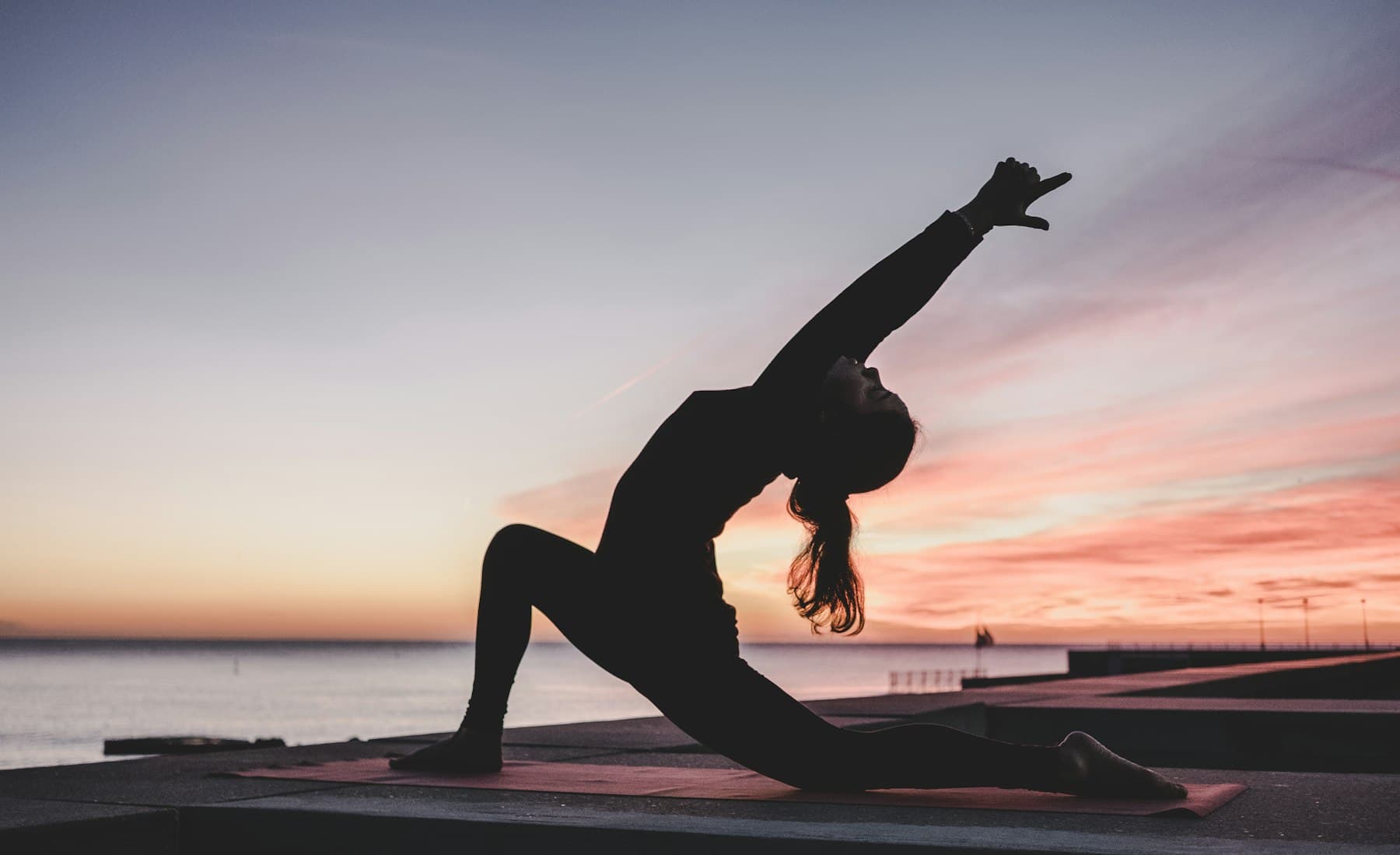 A diverse group of people practicing yoga in a premium, sunlit wellness studio.