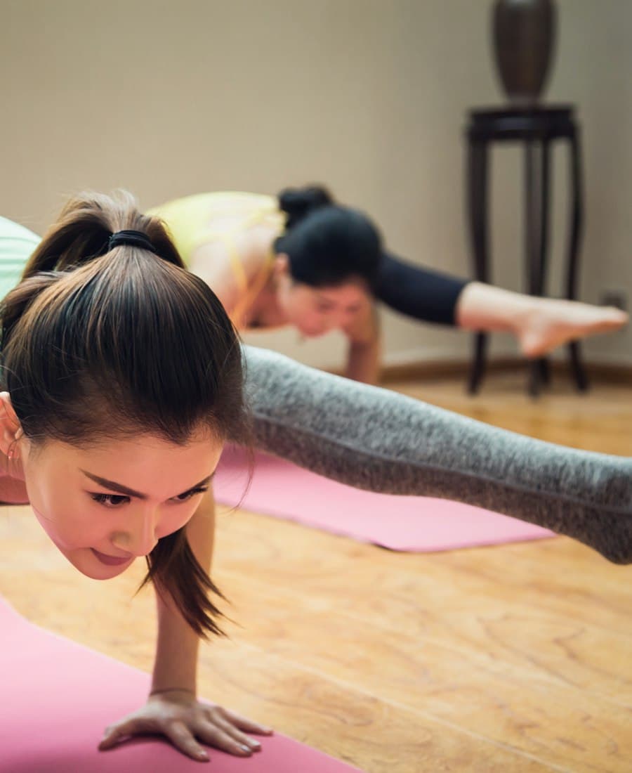 A high-quality teal yoga mat rolled out on a wooden floor.